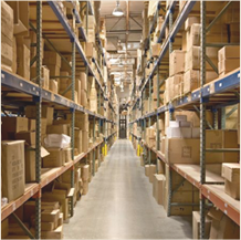 A long warehouse aisle at Smith-Southwestern stacked with floor-to-ceiling pallet racks holding wholesale souvenir and promotional product inventory