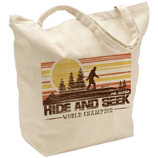 A custom natural canvas tote bag featuring a retro sunset Bigfoot graphic with the text Pine, Arizona, HIDE AND SEEK WORLD CHAMPION