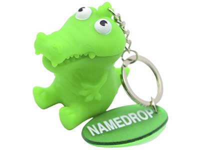 A wholesale bright green cartoon alligator keychain featuring a separate oval nametag that reads NAMEDROP