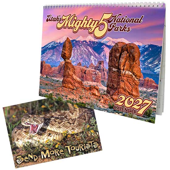 A wholesale 2027 Utah's Mighty 5 National Parks spiral calendar next to a souvenir postcard featuring a rattlesnake and the humorous text Send More Tourists